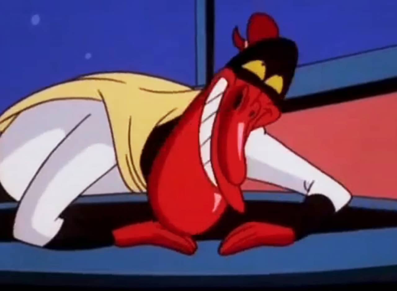 Red Guy in a superhero costume, leaning on a desk