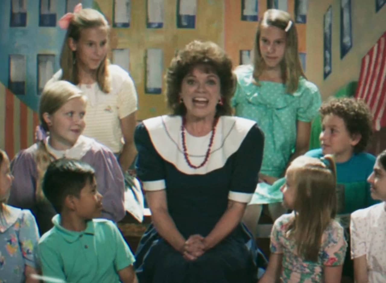 woman host of the show surrounded by kids