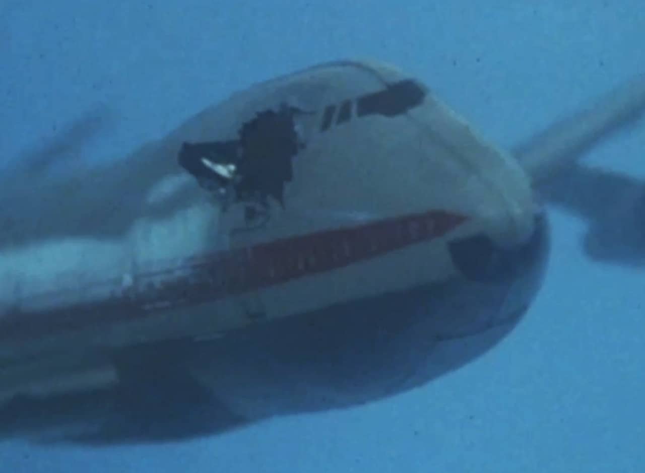 a plane flying in the air with a giant hole in the side of it