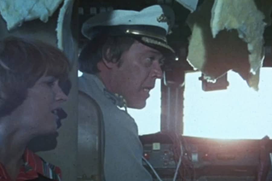 a pilot talks with a flight attendant in a trashed cockpit