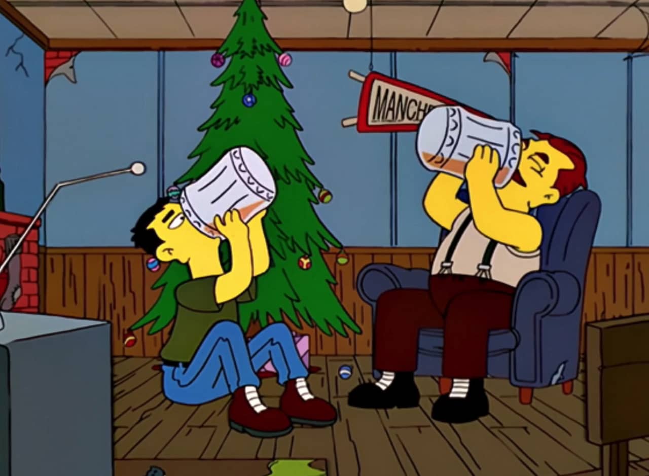 two guys in a living room at Christmas drinking two huge glasses of beer
