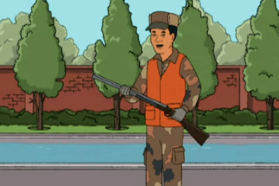 Dr. Money wearing hunting gear and holding a rifle