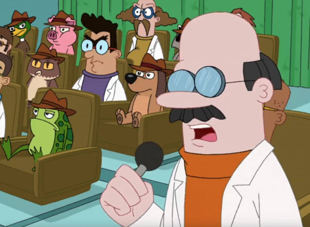 Dr. Feelbetter, a bald scientist with glasses, talking into a microphone in front of the studio audience