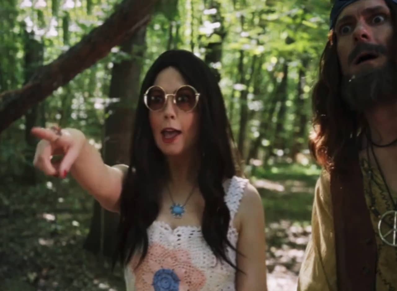 hippie couple in the woods, the woman is pointing at something