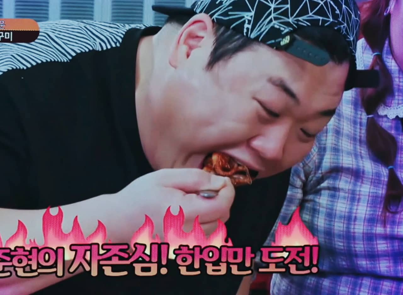 Kim Joon-hyun shoving a spoon of octopus into his mouth