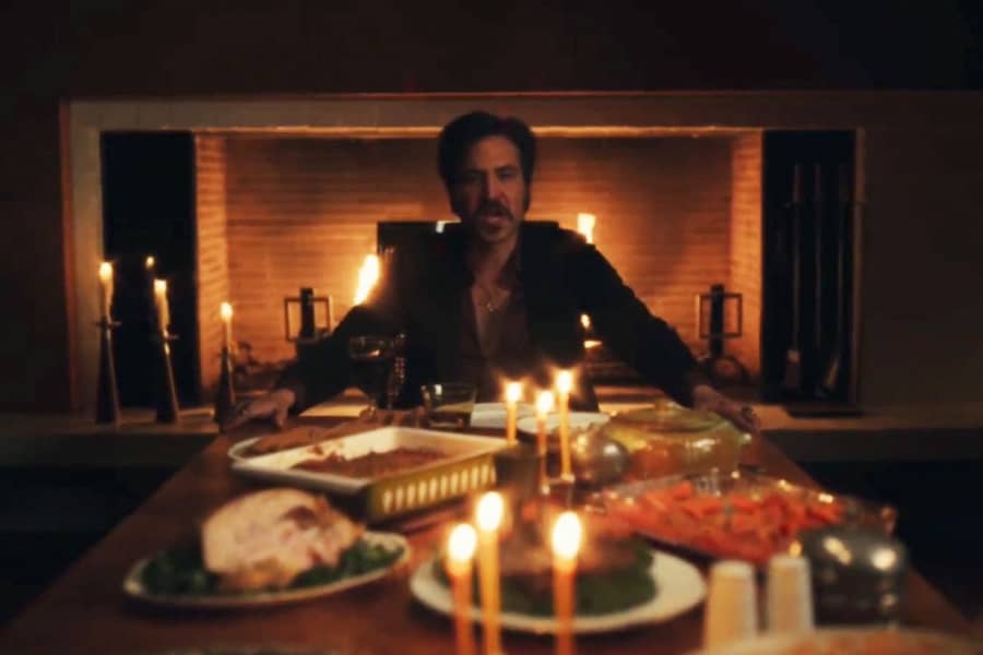 Lonny sitting at a dinner table lit by candles and a fire behind