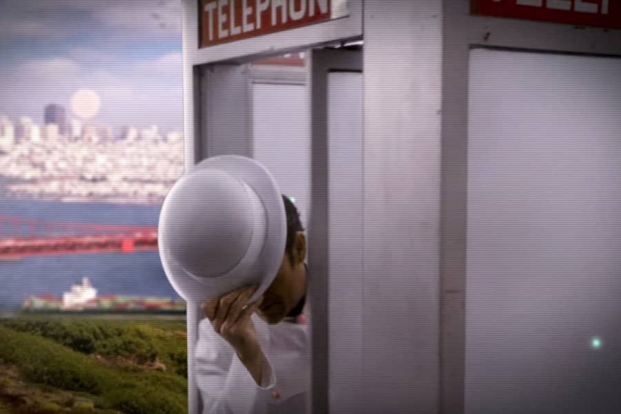 a man in a white hat emerges from a phone booth