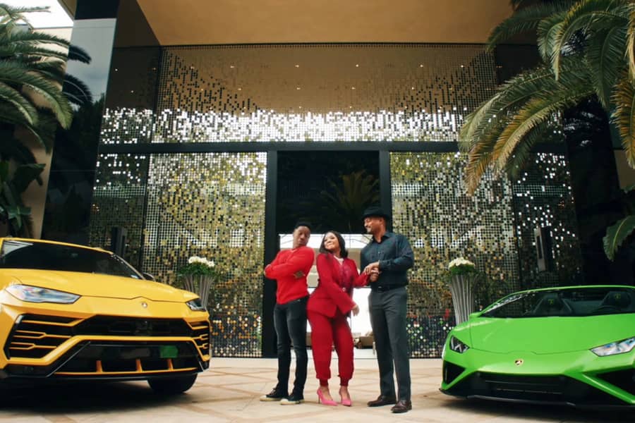 The Thorsens in front of a huge house and two fancy cars