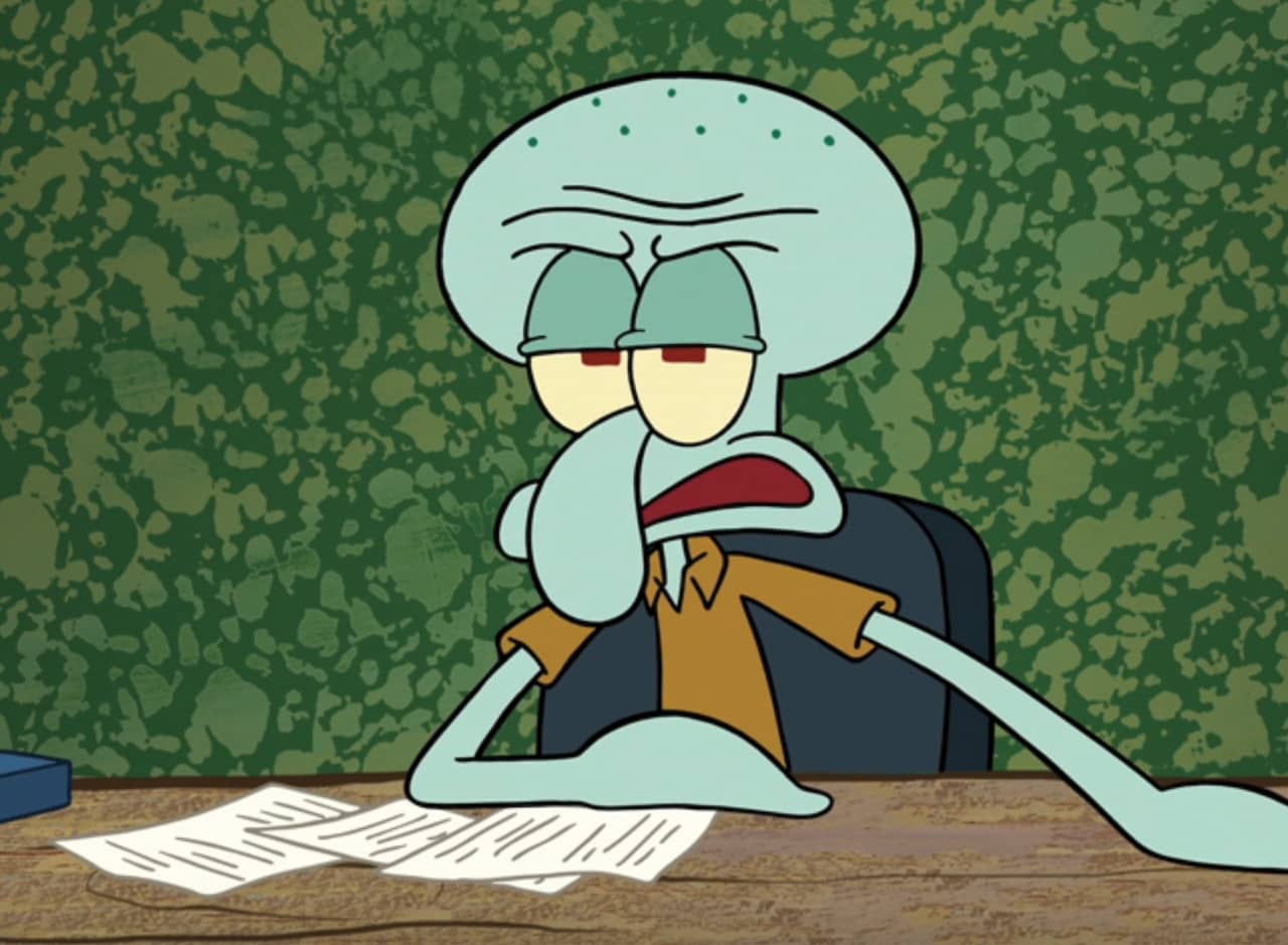 Squidward looking frustrated at a desk