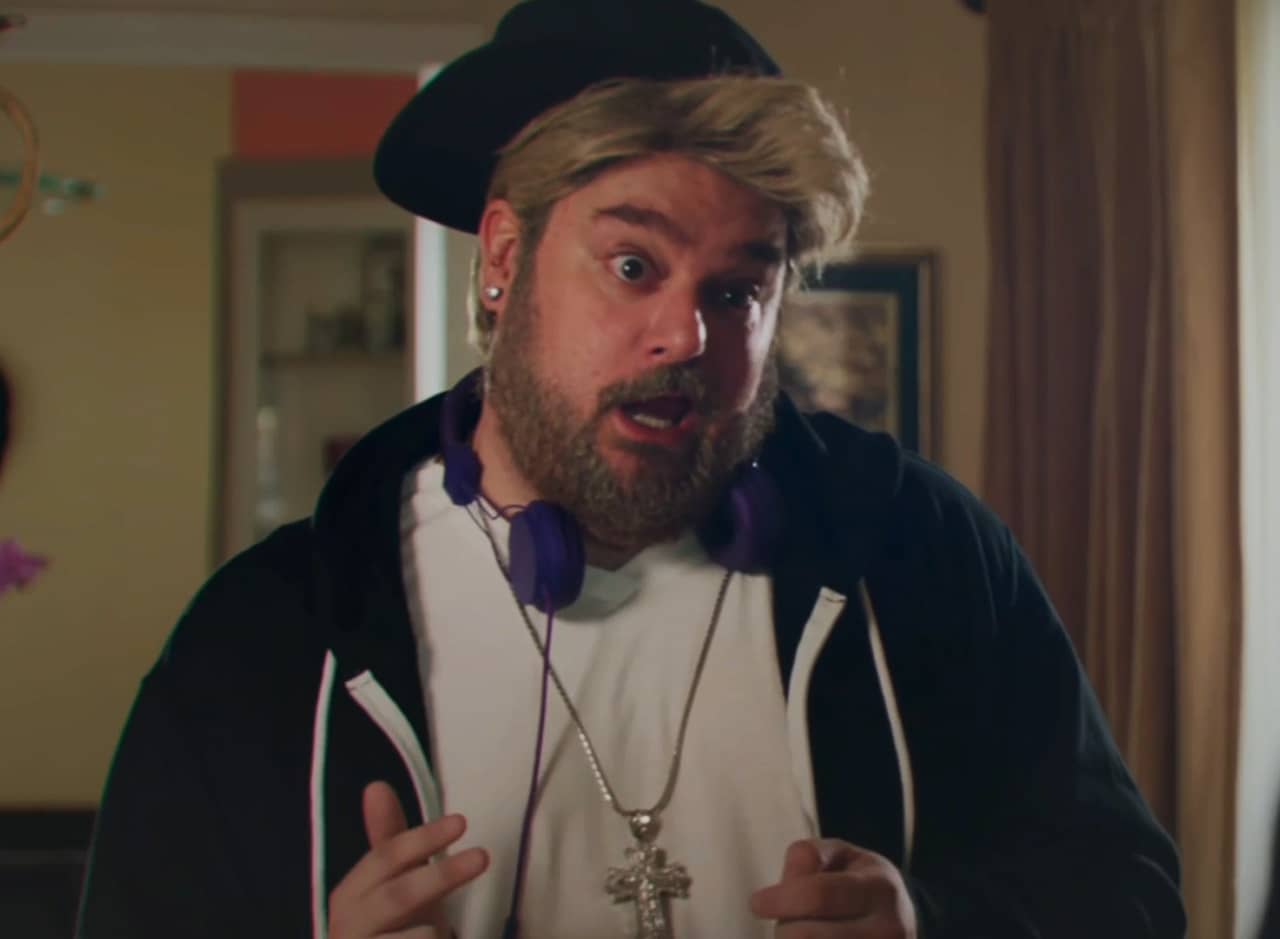 Bobby Moynihan as grown-up Justin Bieber wearing a hoodie, hat, and headphones