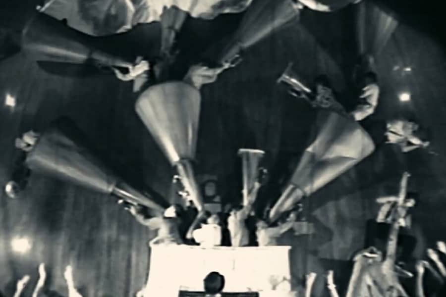 Fats playing organ in an exaggerated scene with many people blowing pipes