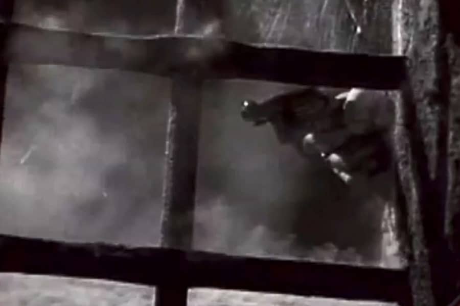 a gun shooting around a corner, through a metal grate