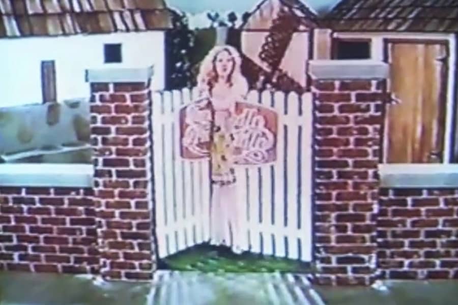 Miss Trudy enters a gate to a storybook set