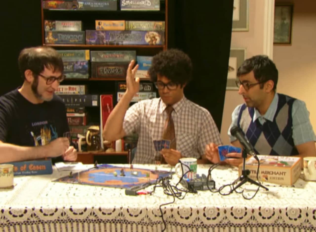 Maurice, Newton, and Booth play board games on a frilly table cloth