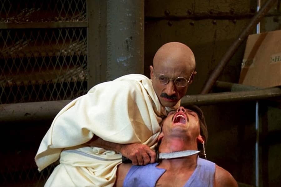 Gandhi holds a knife to the kneck of another guy