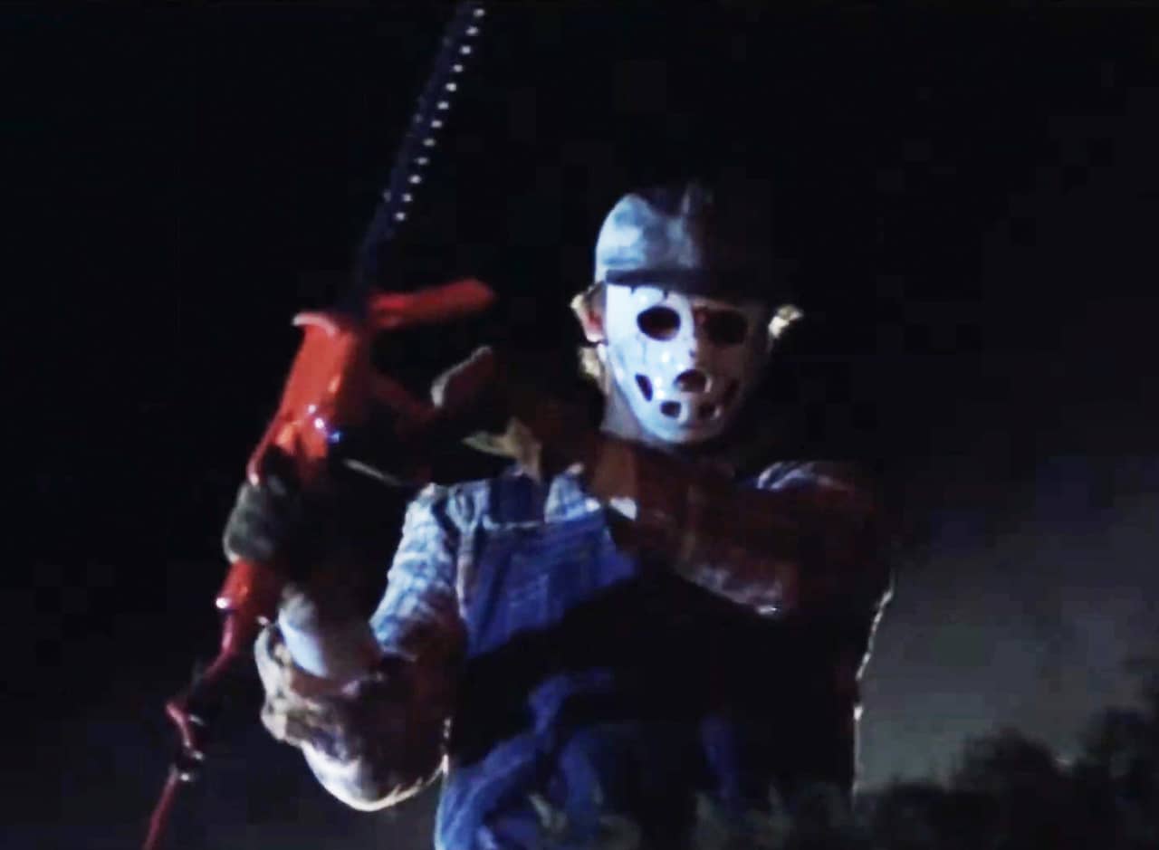 man in overalls and hockey mask wields a chainsaw