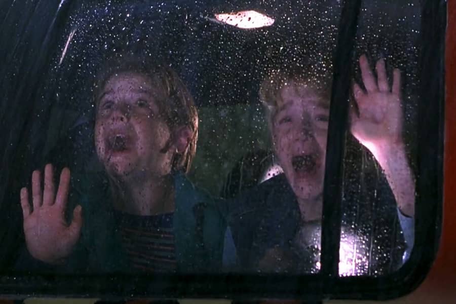 two kids cry and scream inside a rainy Jeep window