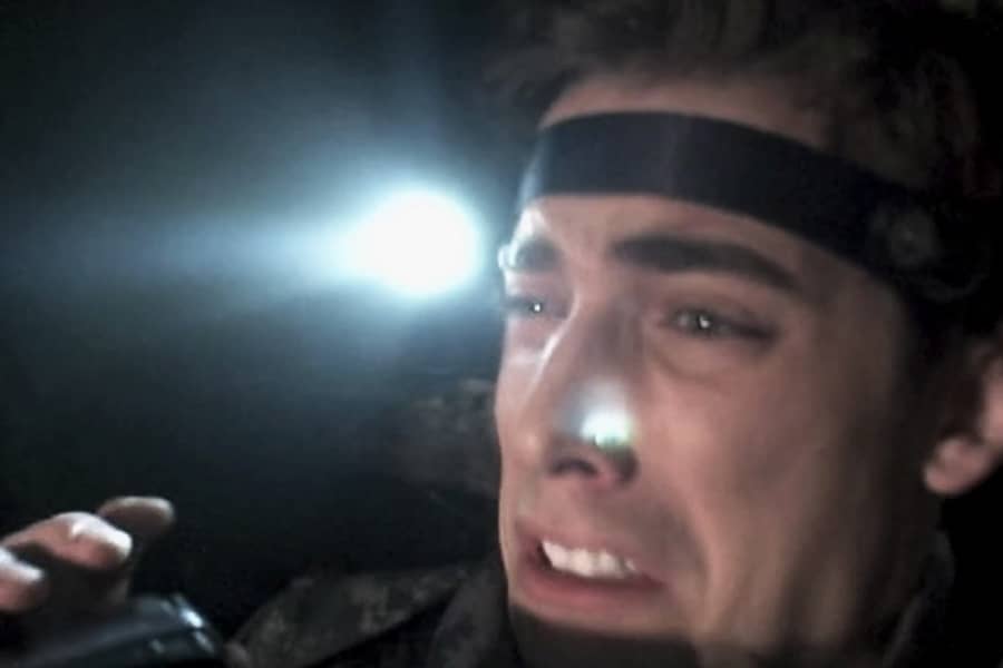 a scared Alan wears a headlamp and holds a video camera