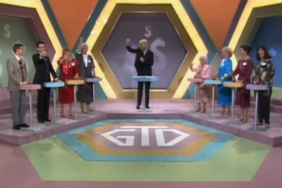 game show set with two teams of four facing off at podiums