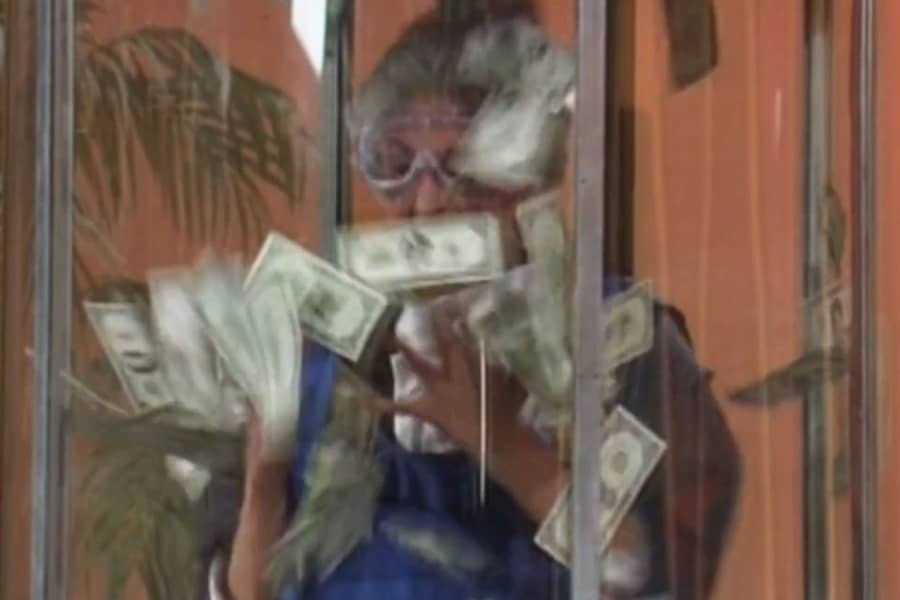 a contestant grabs dollars in a wind booth