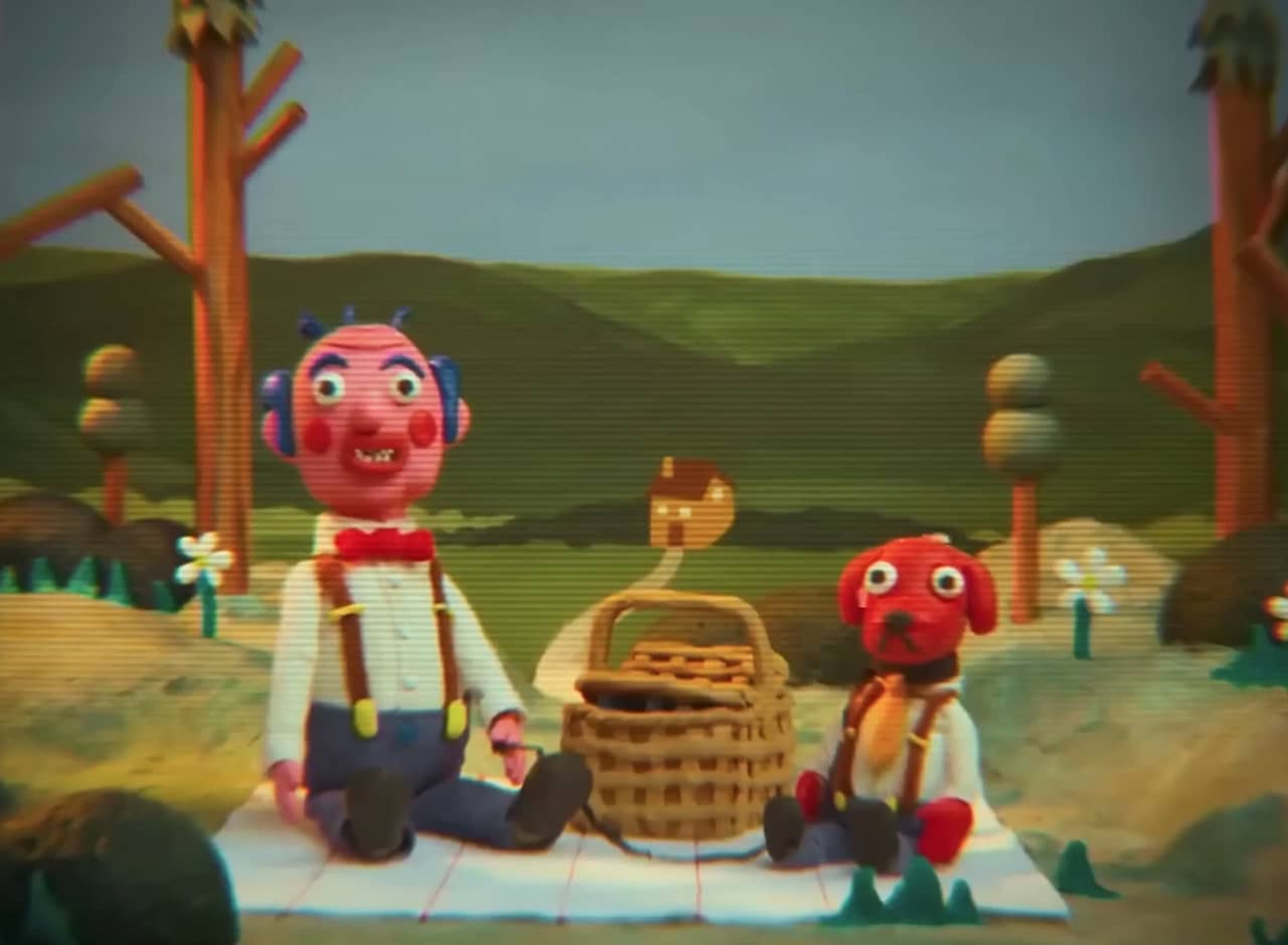 claymation man and dog having a picnic in the woods