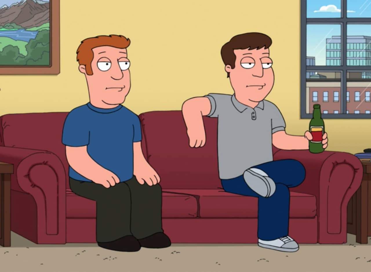 two expressionless guys sitting on the couch