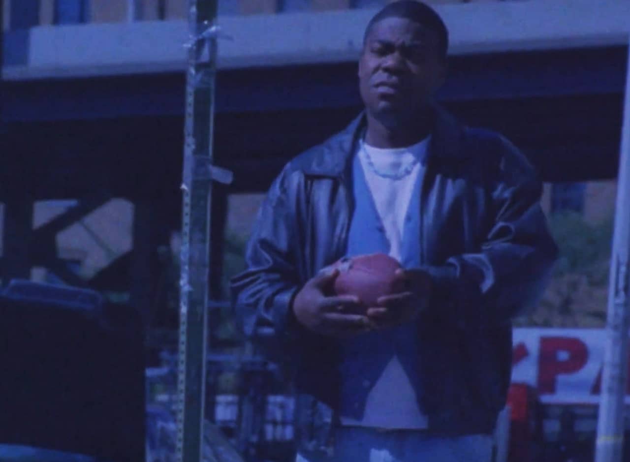 Tracy Jordan as D’Jeffrey “Lucky” Seeda, walking down the street and holding a football
