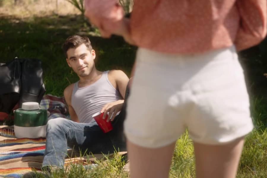 Corey, a teen boy, laying on a picnic blanket with Tori standing nearby