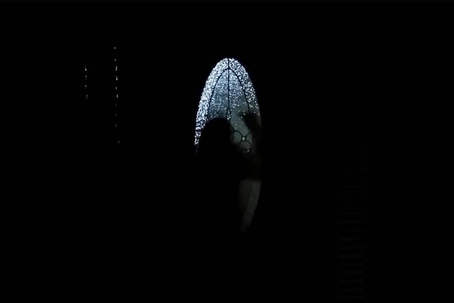 silhouette of a person looking into the window of a front door at night
