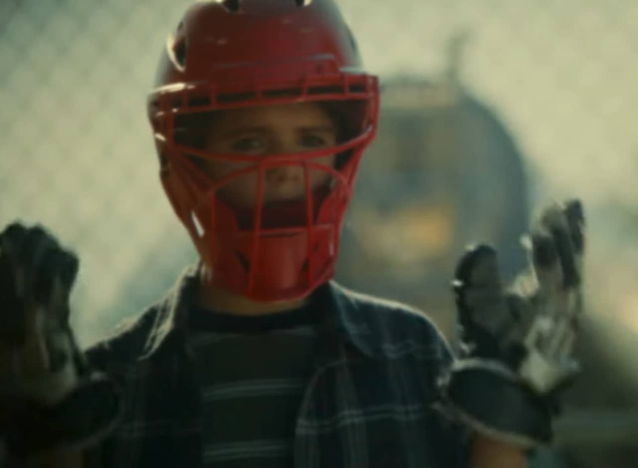 a kid wearing street clothes, hockey gloves, and hockey helmet