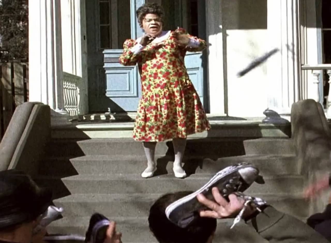 Tracy Jordan as a white grandma on a front stoop while a crowd throws shoes at her