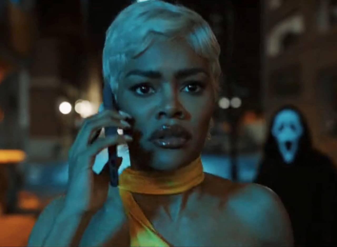 Teyana Taylor on the phone in a dark alley and Ghostface is standing behind her
