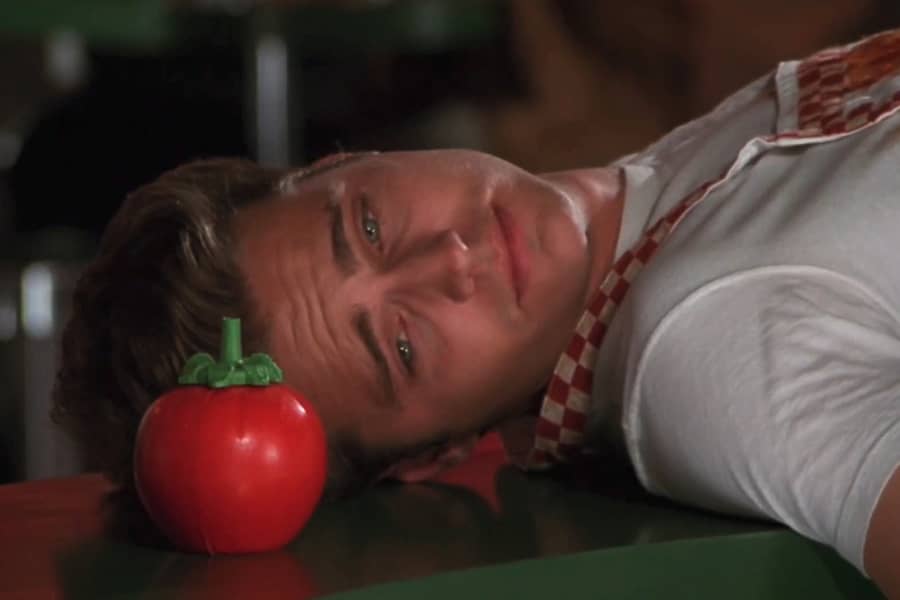 teen boy looks dejected, lying on a countertop next to a tomato ketchup bottle