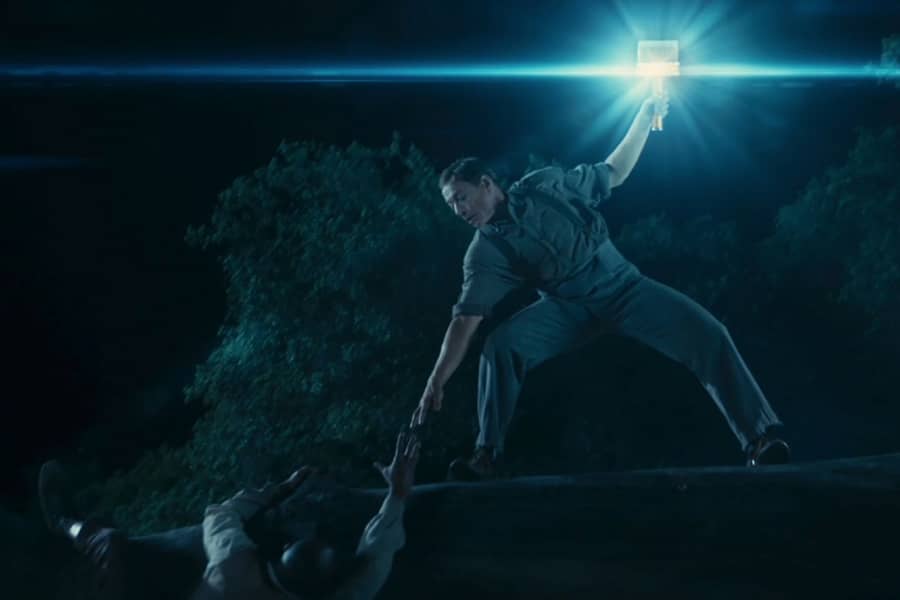 Huck on a big tree branch holding up a paintbrush that is glowing blue