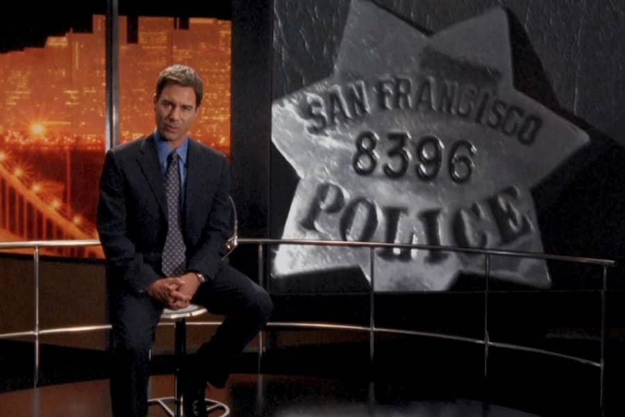 Novak on set with a screen behind showing an SFPD badge