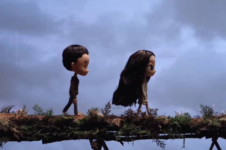 girl and boy walk single file across a big log