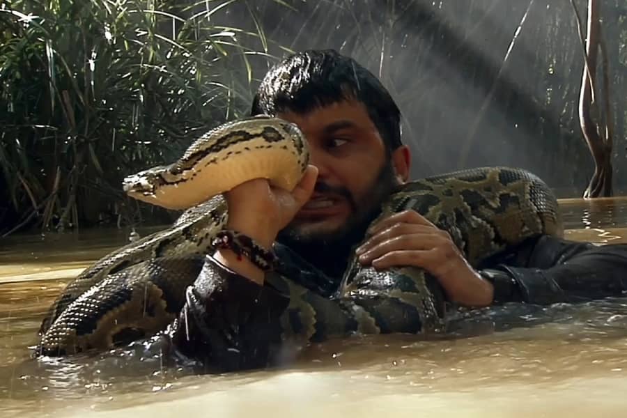 Jack Mimoun in a swamp with a snake around his neck
