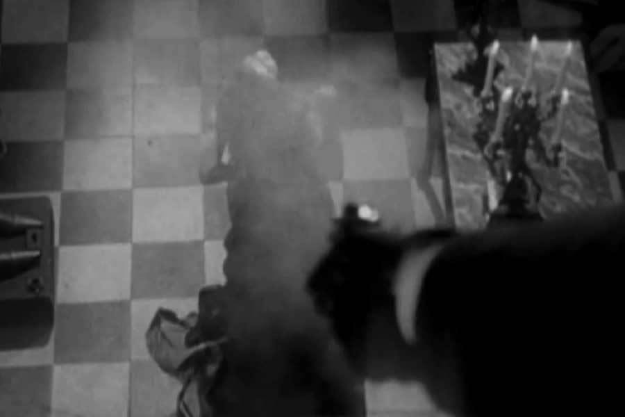 a gloved hand shoots a gun at a woman on the floor