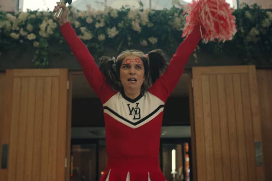 Joan interrupting a wedding in her cheerleader uniform, pigtails, and a penis drawn on her forehead
