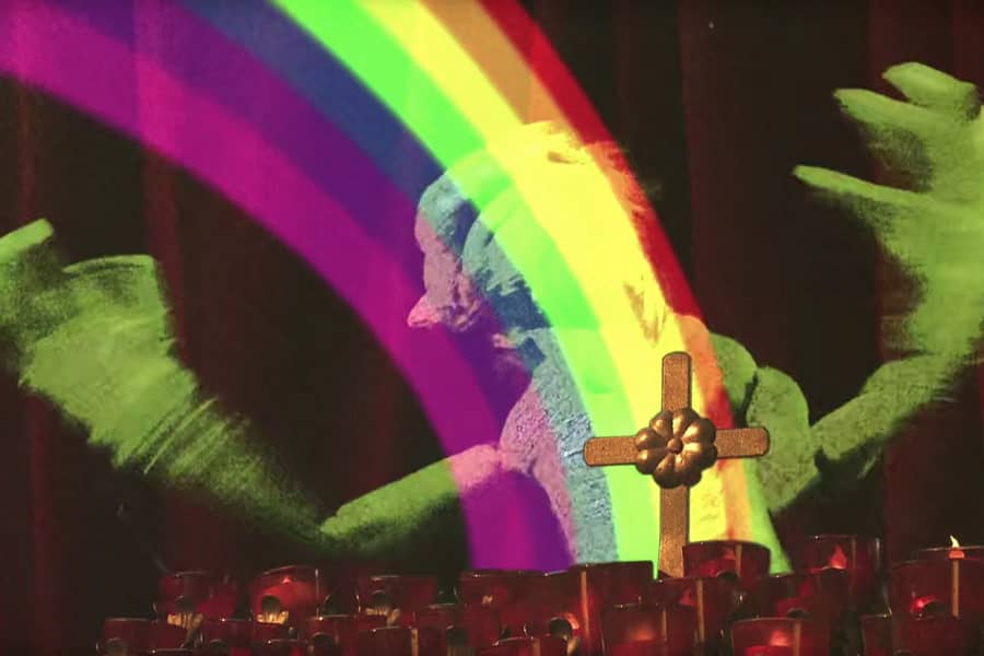 a gremlin in a church flails as he is touched by a rainbow