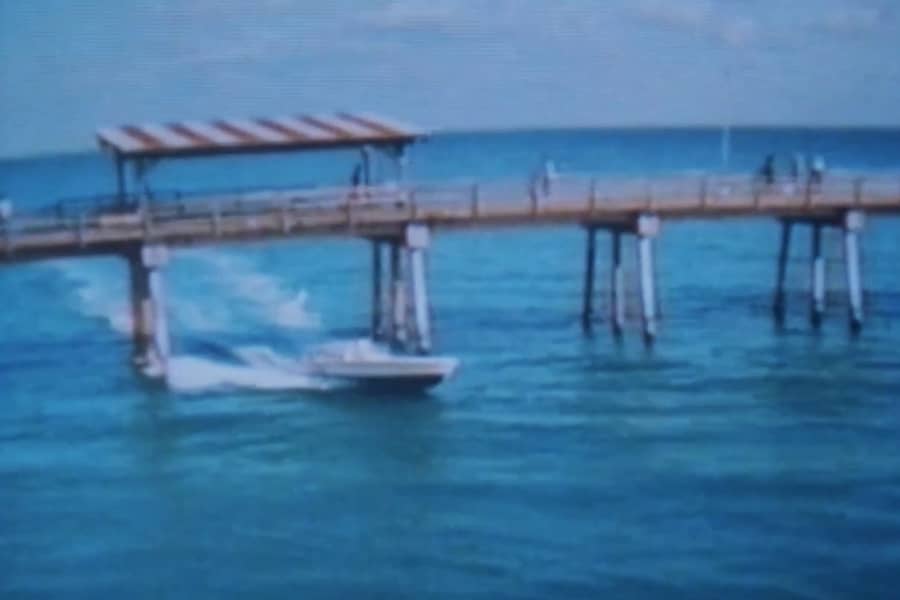 a speedboat drives beneath a pier