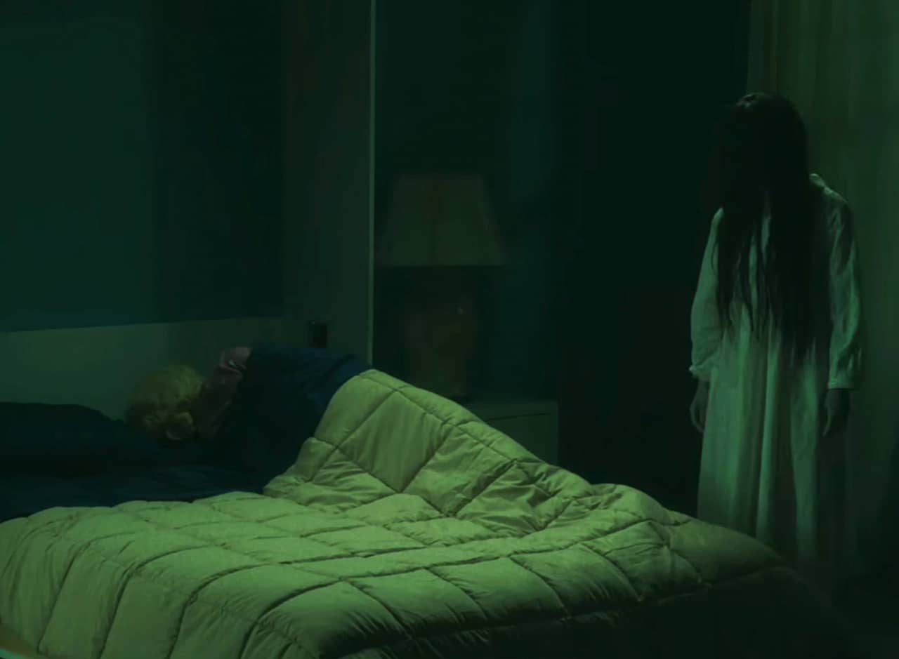 night vision show of the Ring girl with long black hair standing next to a person asleep in bed