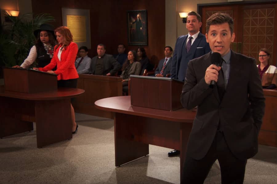 host speaking into a microphone in front of people in the court