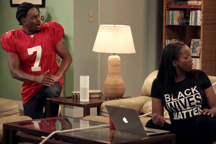 Kev’yn kneels in a Colin Kaepernick jersey and Yolanda wears a “Black Wives Matter” t-shirt