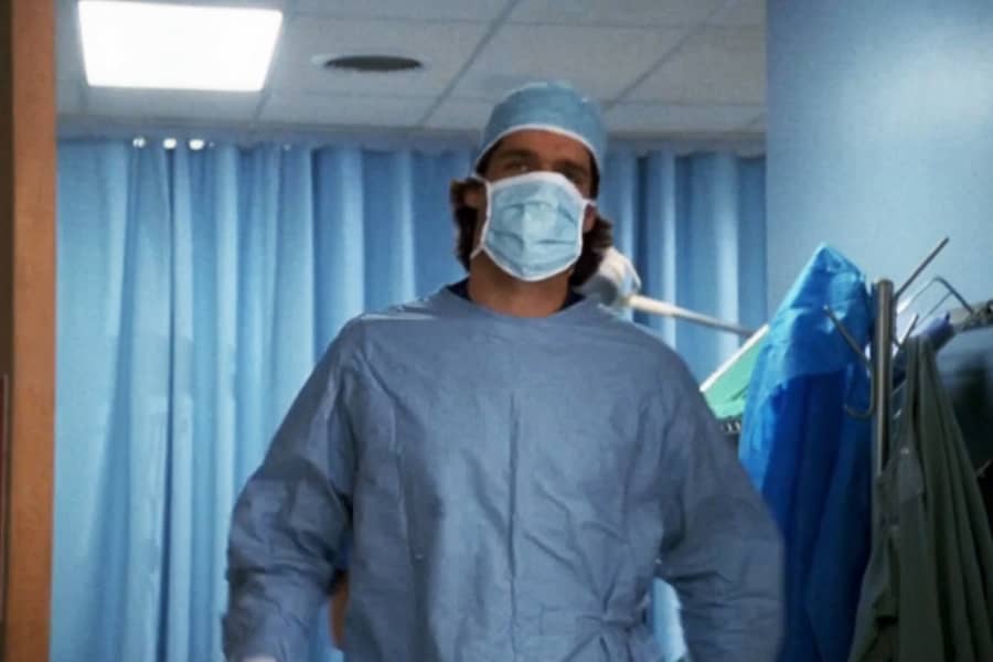 Dr. Chambers in scrubs and mask walking out of the operating room