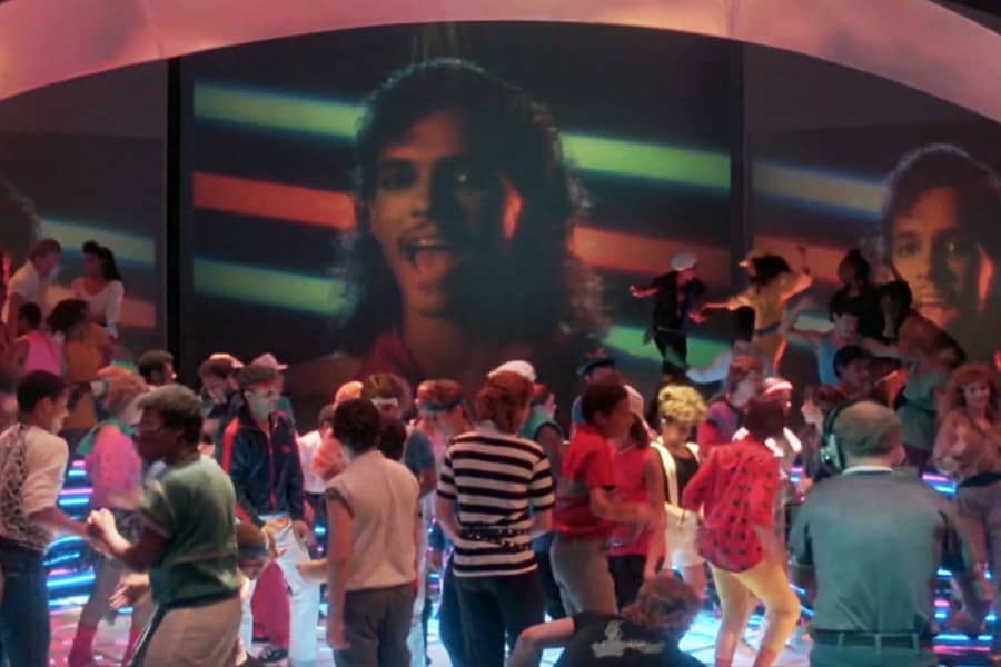 people dancing with a music video playing on a giant screen