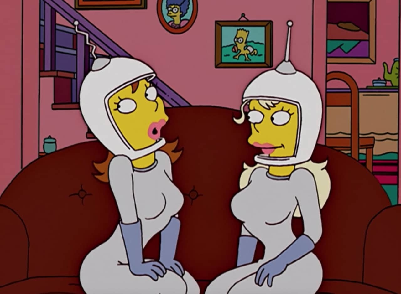 two sexy women in space costumes sit on the Simpsons’ family room couch