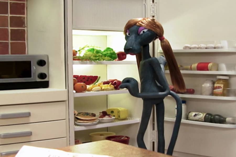 Minou wearing a long wig and looking in the fridge