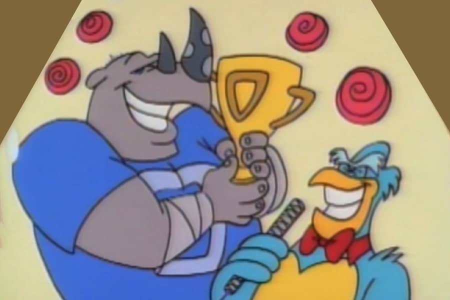 Screech with a football playing rhino holding a trophy