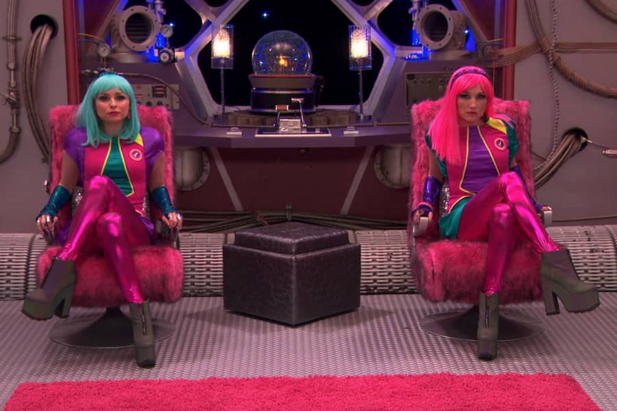 Linda and Heather sitting in command chairs on their spaceship